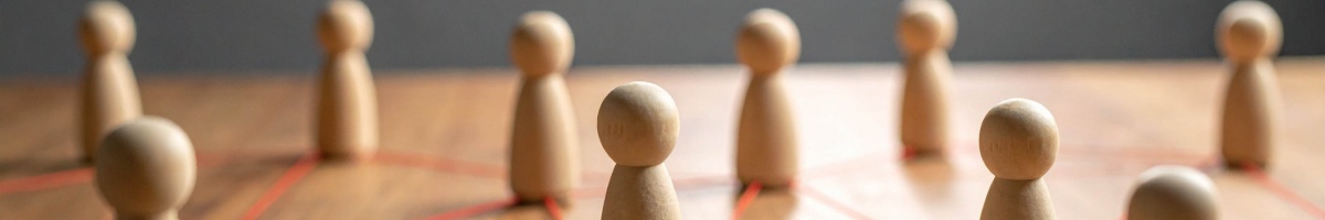 Several wooden figures representing individuals spread across a table and connected with red thread.