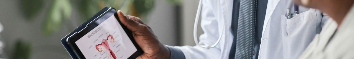 A medical provider shares a tablet displaying the female reproductive system with a patient.
