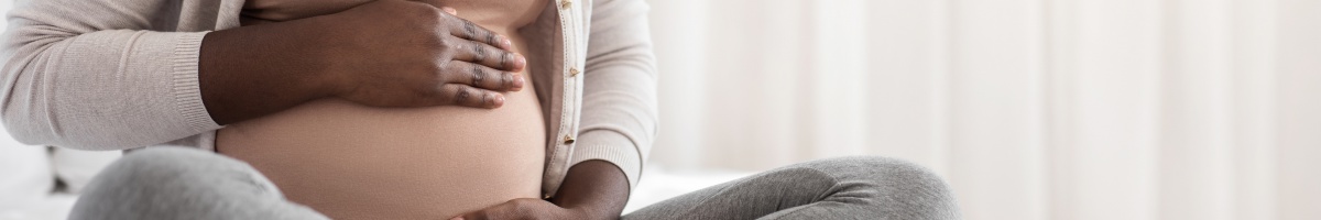 A pregnant woman cradles her stomach.